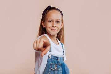 Portrait of smiling happy child girl pointing finger at camera. Childhood, student, lovely, adorable girl of ten years old. - Powered by Adobe