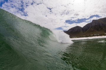 Fototapeta na wymiar perfect surfing wave with a mountain background