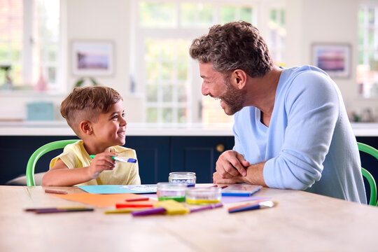 Mature Father At Home In Kitchen With Son Painting Picture Together