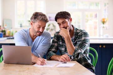 Same Sex Male Couple Using Laptop At Home To Check Domestic Finances