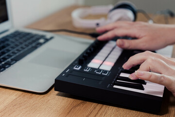Obraz na płótnie Canvas Midi Keyboard musician hands playing midi keyboard for arranging music on laptop computer Music production technology concept