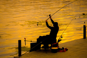 A fisherman is fishing on a spinning rod on the city embankment. 