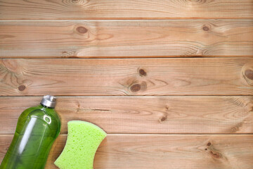 Dishwashing gel and kitchen sponge on wooden background. Space for text. Flat lay. House cleaning...