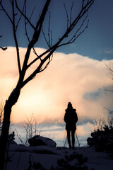 Hiking woman silhouette over the horizont at sunset