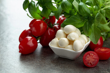 Mozzarella cheese with basil and tomatoes on an old stone table.