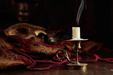 Still life with an extinguished candle and carnival masks.