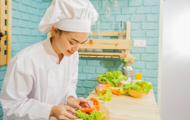 Asian woman in chef's uniform is cooking in the kitchen.