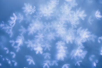Fototapeta na wymiar Christmas or New Year abstract magic lights background, white snowflakes bokeh on blue as winter holiday backdrop. Xmas mood aesthetic photo, blurred effect, celebration illumination