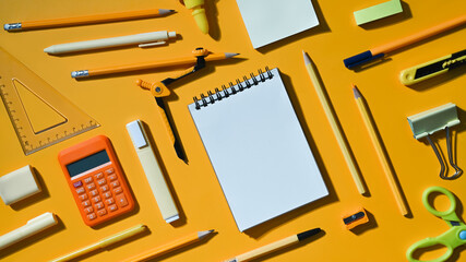 Blank notepad and various school supplies on yellow background. Flat lay, Top view