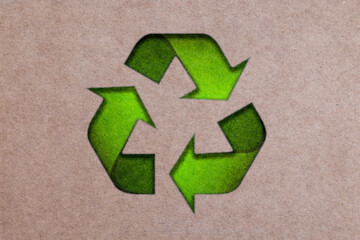 The three green arrows going in a triangle, international recycle symbol on Brown Cardboard. Paper or cardboard eco friendly