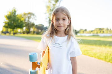 smiling kid skater with skateboard outdoor. Hipster girl with penny board. 