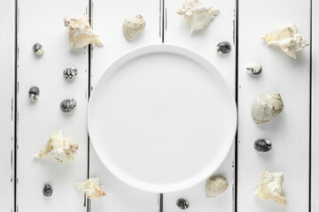 White plate with seashells on white wooding background, wallpaper