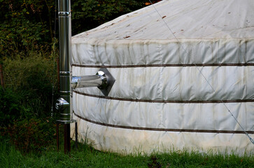 Wood heating in a Mongolian yurt-type circular tent. The white tarpaulin into which the stainless steel pipe of the chimney to the fireplace enters. they drown here with wood or yak dung, meadow