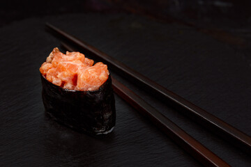 Warm rolls with tuna, salmon, perch, eel, tobiko caviar, nori, rice, cucumber on black background.