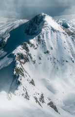 Beautiful high snowy mountain peak from above in the Austrian alps during a sunny afternoon.