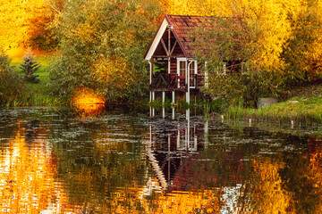 Red holiday cabin with reflection in the pond during sunset