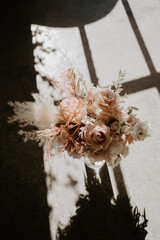 wedding floral bouquet for bride with nude and pink flower tones in from of the window