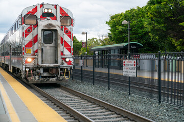 California, USA - May 16, 2018: diesel locomotive of CalTrain approaching platform at the station on a cloudy day. commuter rail line serving in San Francisco - obrazy, fototapety, plakaty