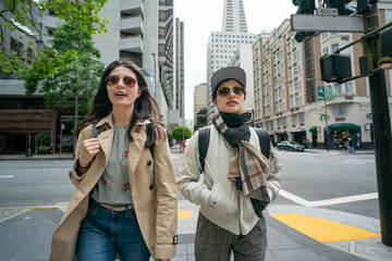 Obraz premium closeup up of two leisure asian Japanese businesswomen taking relaxing stroll back to office at street corner after having lunch together in downtown san Francisco California usa