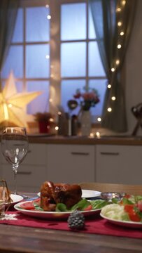 Vertical Screen: romantic table setting dinner ready for two in cozy atmosphere at home with decorated Christmas tree and LED lights on blurred background