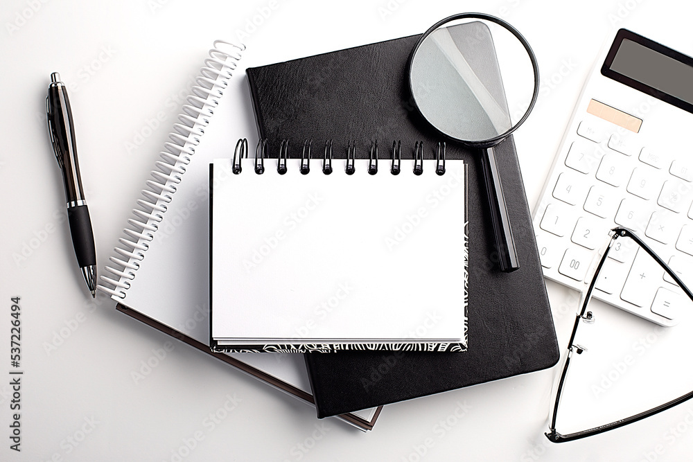 Poster notebook with calculator, magnifier and pen on table, copy space