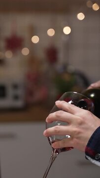 Vertical Screen: selective focus of a Japanese maleâs hand serving and swirling wine in the wineglasses while his wife is looking on blurred background at the indoor romantic dinner date