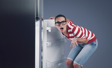 Disappointed hungry woman and empty fridge