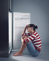 Desperate hungry woman and empty fridge
