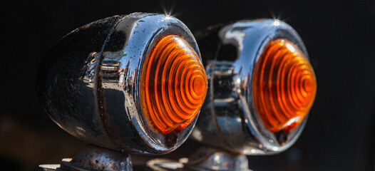 Turn signals on the chrome bumper of a black retro car. Details of the exterior of a vintage car....