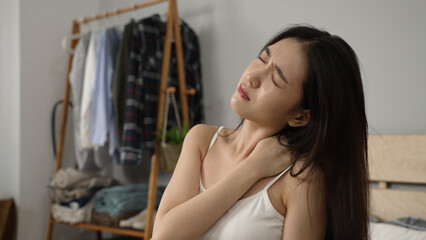 shoulder shot of a Korean girl exercising her stiff neck muscles and massaging her painful...