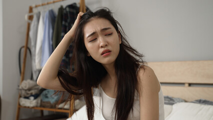 upset asian chinese female feeling migraine and coping with terrible hangover after getting up in...