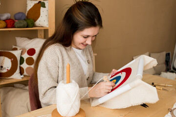 Punch needle embroidery. Young woman pushing the punchneedle straight down into the foundation...