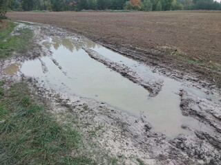 Dirt on a field in the village after rain and traces left by a tractor