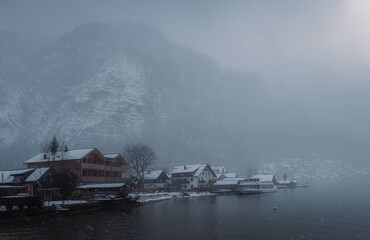 Typical alpine style buildings in the distance over the lake in Hallstatt, Austria during a snowy winter afternoon.