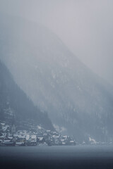 Typical alpine style buildings in the distance over the lake in Hallstatt, Austria during a snowy winter afternoon.