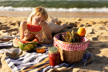  Cheerful young woman enjoy at tropical sand beach. Portrait of happy girl with fruit. Young woman having a picnic on the beach