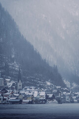 Typical alpine style buildings in the distance over the lake in Hallstatt, Austria during a snowy winter afternoon.