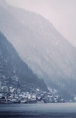 Typical alpine style buildings in the distance over the lake in Hallstatt, Austria during a snowy winter afternoon.
