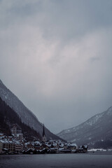 Typical alpine style buildings in the distance over the lake in Hallstatt, Austria during a snowy winter afternoon.