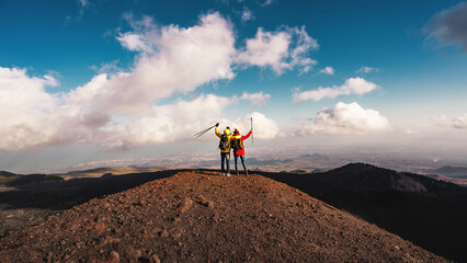 A couple of young hikers look at the lava-rocky panorama from the Silvestri mountains of the Etna...