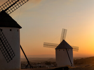 Pair of old windmills located in the town of Campo de Criptana (Spain), on the historic route of the mills of Don Quixote, during a dramatic sunset.