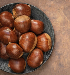 Edible chestnuts on dark rustic background.  Horse chestnuts top view. Flat lay. Autumn food concept