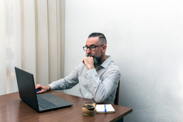 photo of hipster bearded man working with laptop computer at home