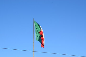 Fototapeta premium Large Italian flag flying against the blue sky