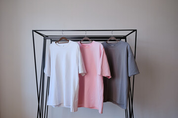 Empty pink gray and white t-shirt on a hanger on a light background. Style and store design concept. Space for copy. Clothes on hangers