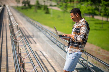 Young african american man with a laptop in the countryside