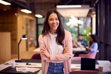 Portrait Of Smiling Businesswoman Standing In Modern Open Plan Office