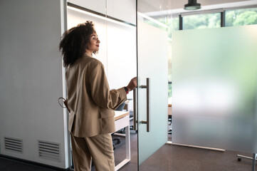 Confident and determined businesswoman entering a modern office with glass doors