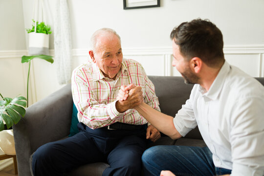 Smiling elderly father and son shaking hands and looking excited