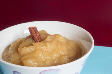 A cinnamon stick on applesauce on a blue and red background. Healthy food.